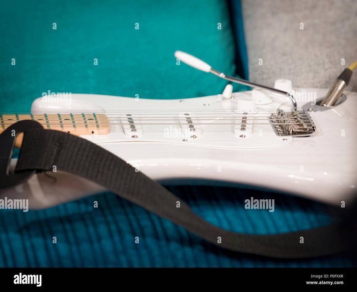 Close up of electric guitar hi-res stock photography focusing on the strings and pickups, which relates to comfort, playability, and longevity of guitar strings.