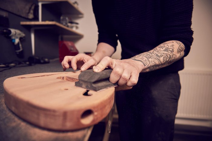 How do I hand sand my guitar body properly before I apply paint?