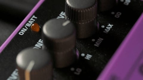 Adjusting guitar pedal knobs to shape your tone.